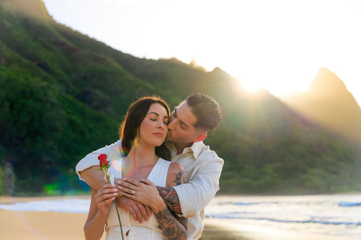 Intimate moments captured on beach with sunset and mountains in background.