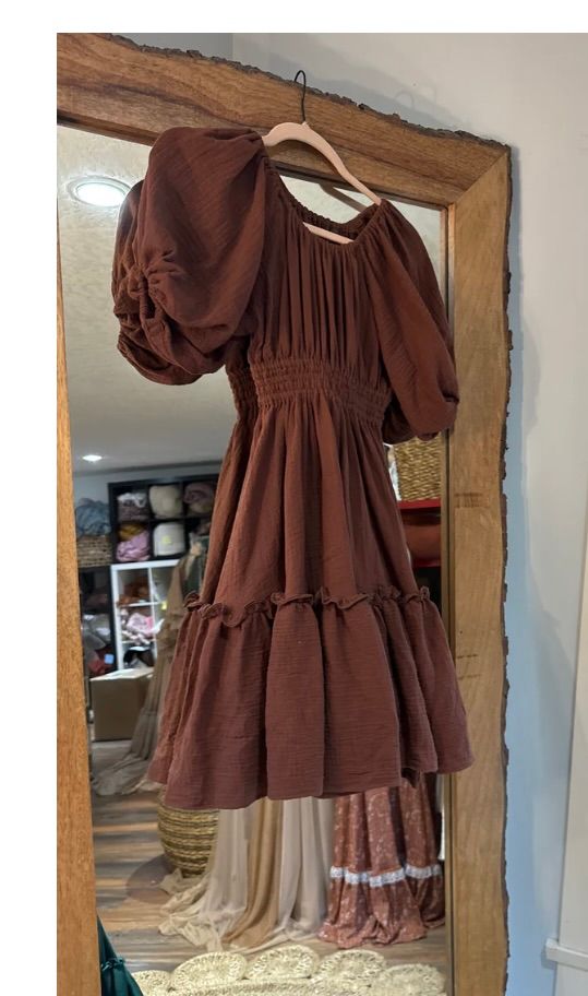 Brown prairie-style dress with puff sleeves displayed on wooden framed mirror.