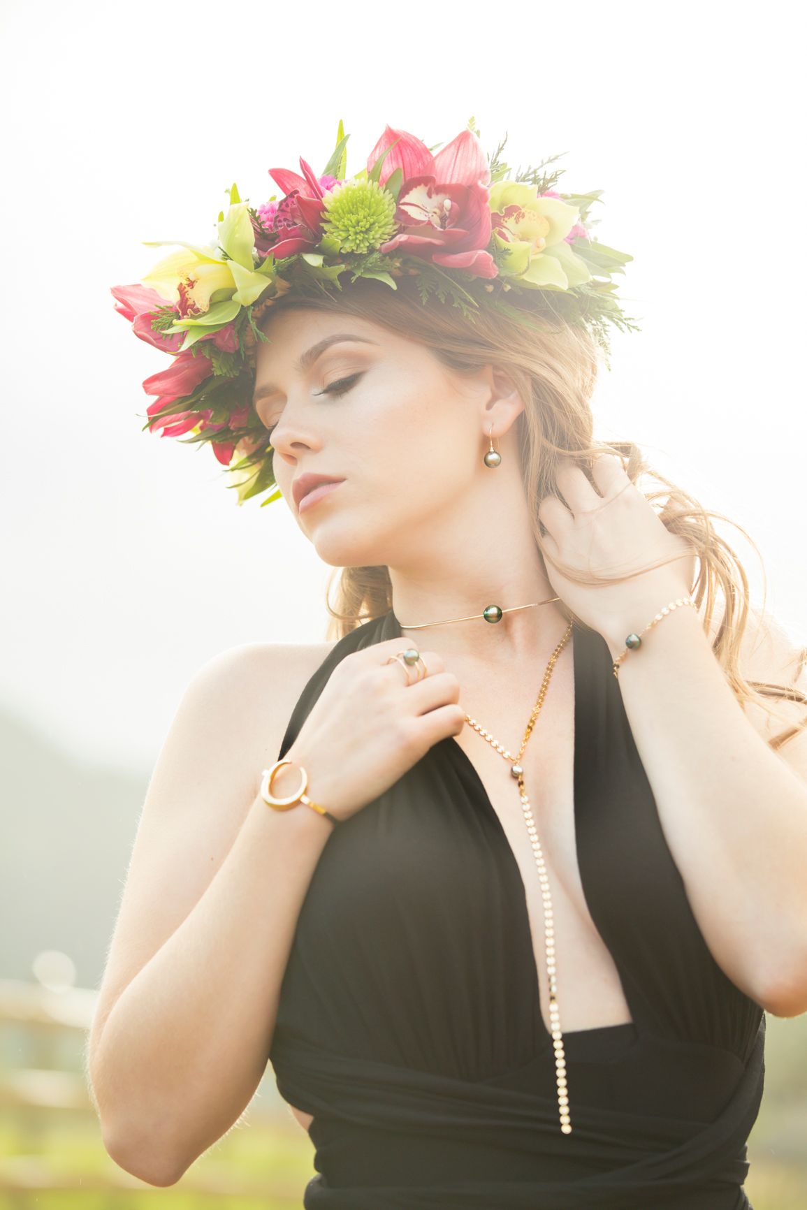 Ethereal portrait of woman wearing floral crown and black dress in soft dreamy lighting.