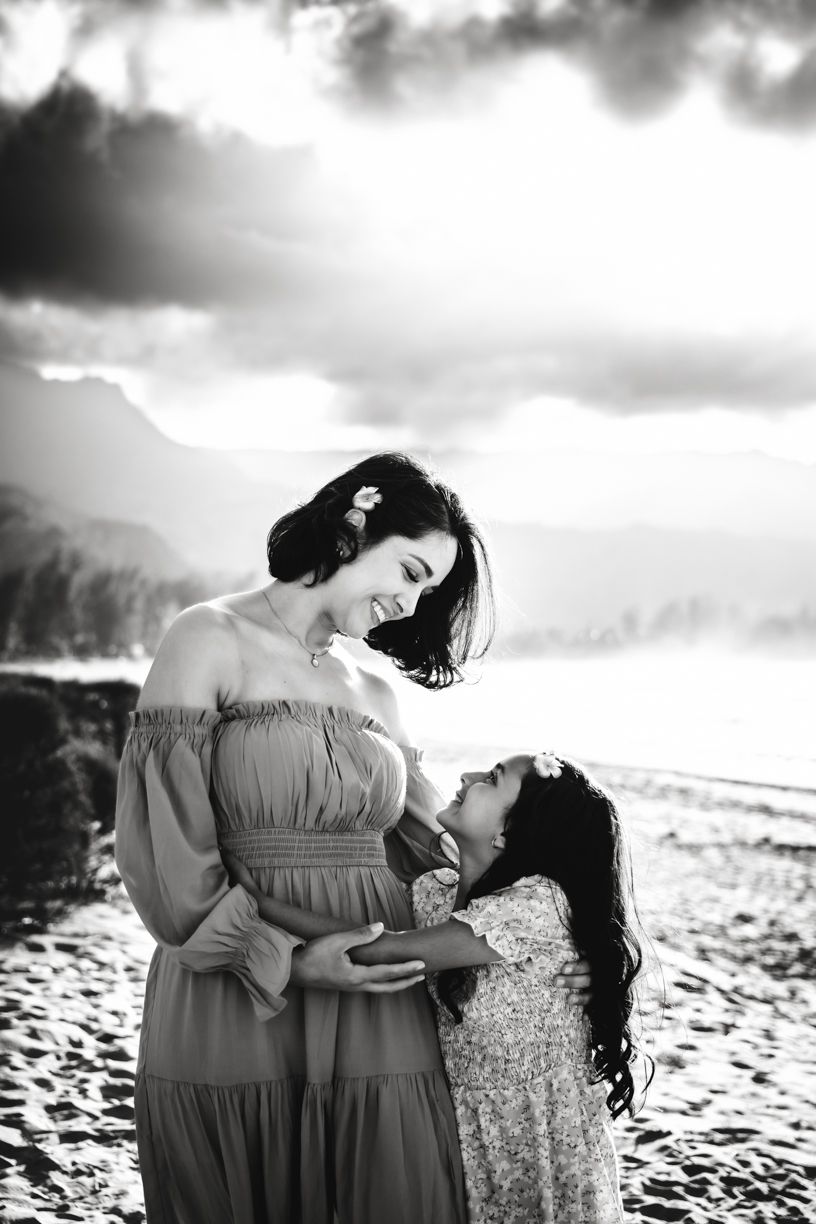 Black and white portrait of people sharing intimate moments on a dramatic beach landscape.