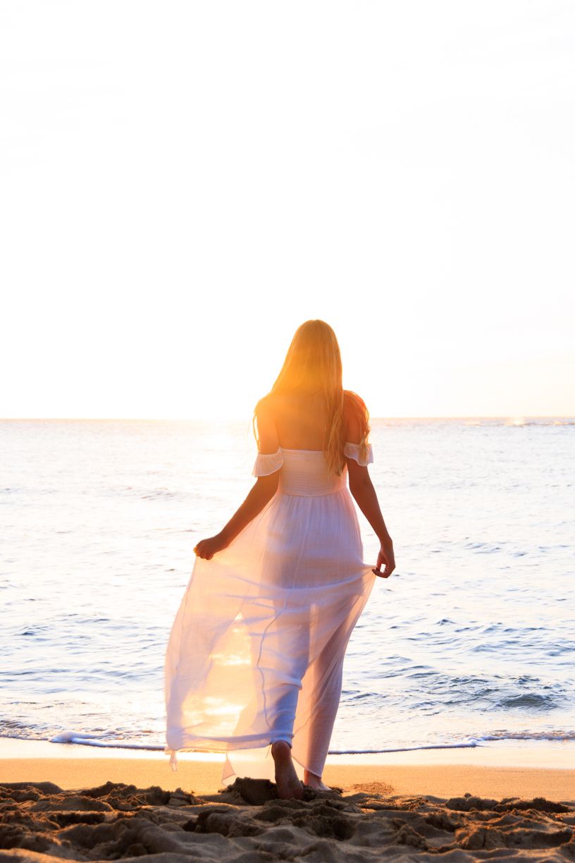 Silhouette photography at beach sunset with figure in flowing white dress.