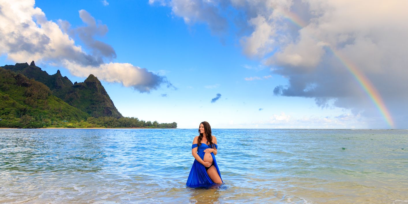 Beautiful beach landscape with rainbow and dramatic clouds over ocean waters.