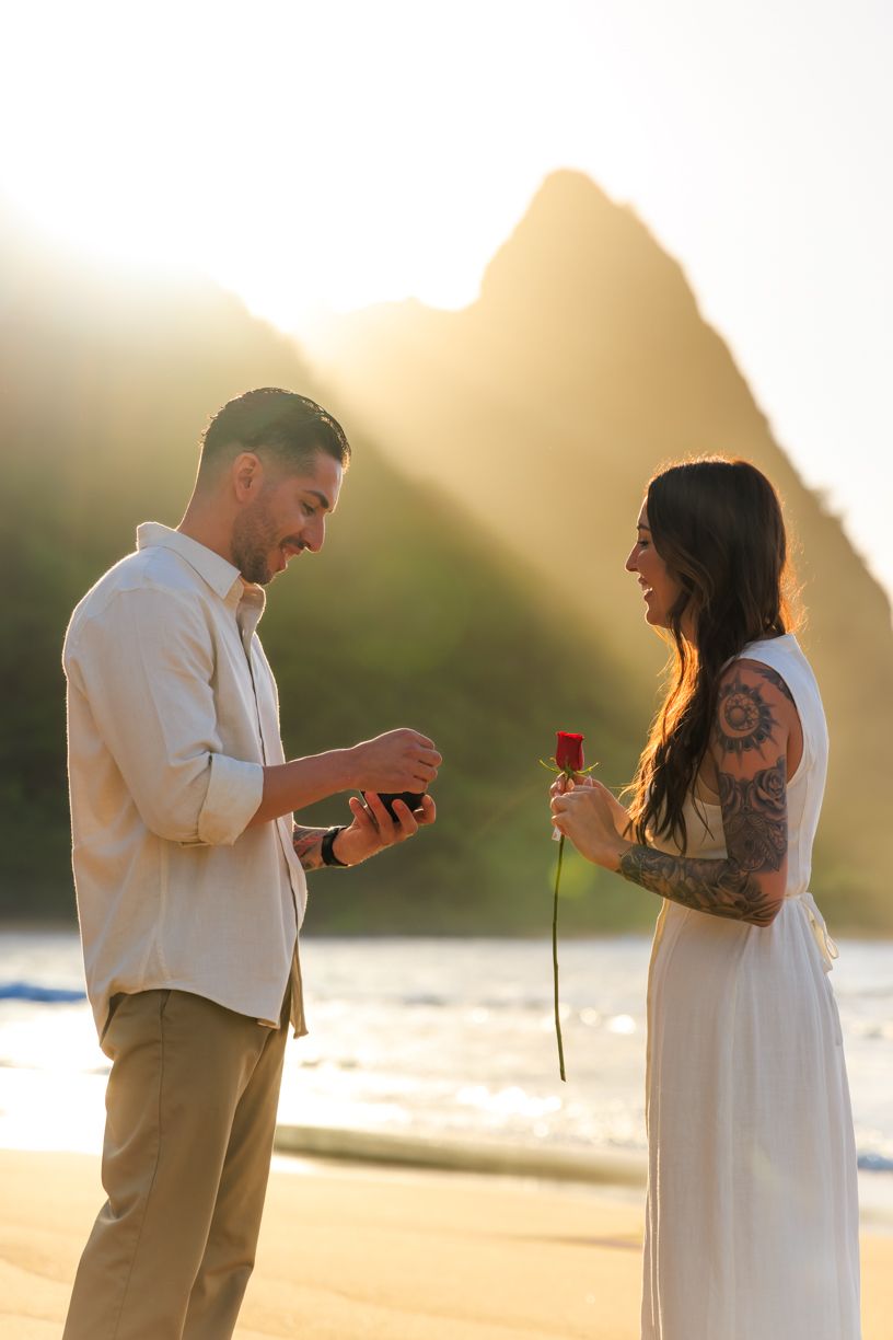 A surprise beach proposal captured in sequence during golden hour with mountains in the background.