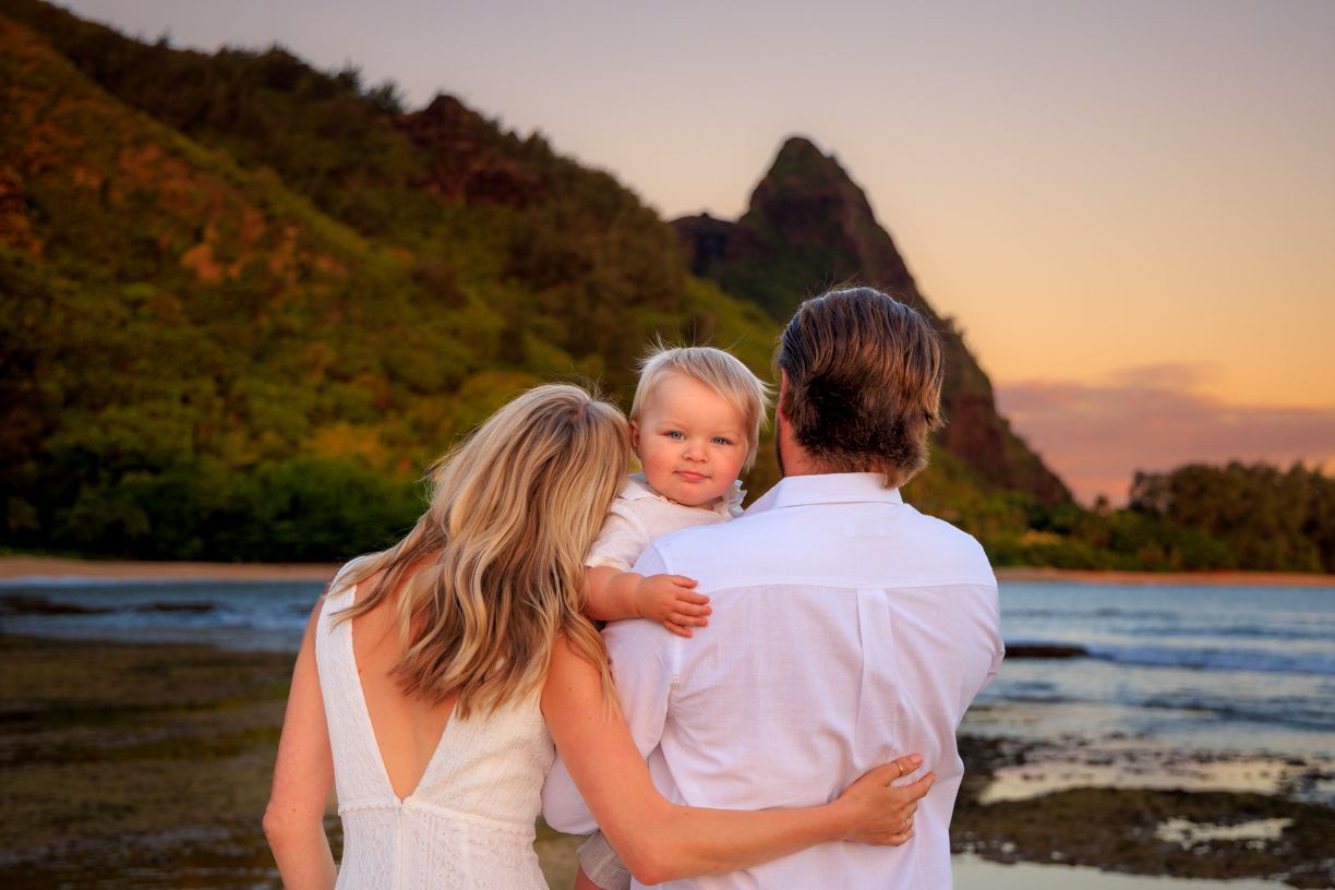 Group enjoying peaceful sunset moment on Hawaiian beach with mountains.