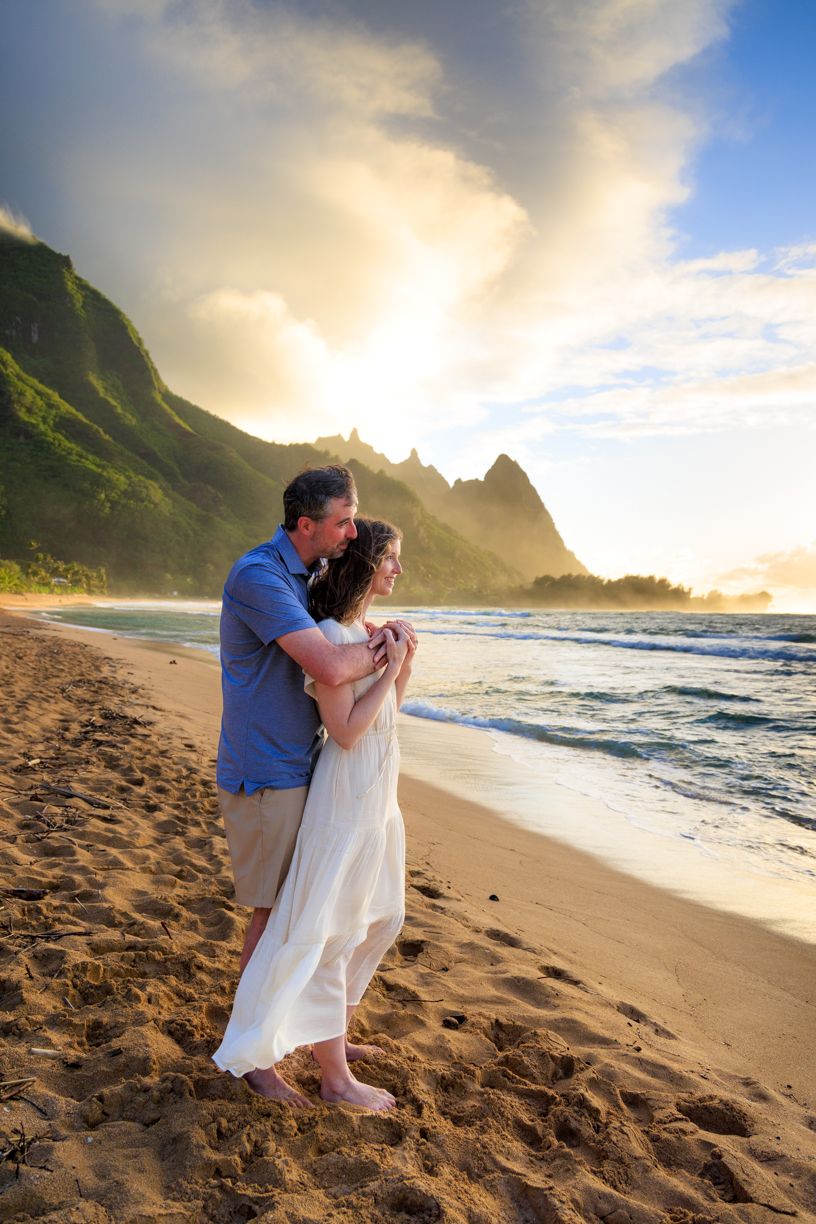 A romantic beach photoshoot at sunset with dramatic coastal cliffs and crashing waves.