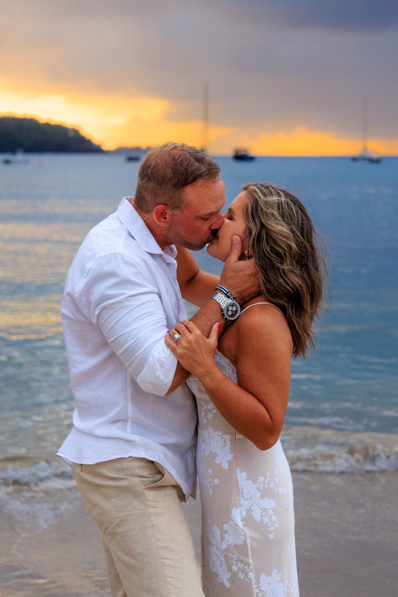 A romantic sunset beach photo with boats anchored in the distance.