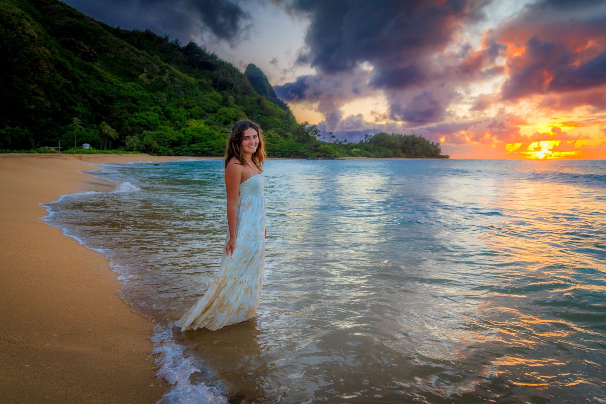 Dreamy coastal scene with waves lapping at sandy beach during vibrant Hawaiian sunset.