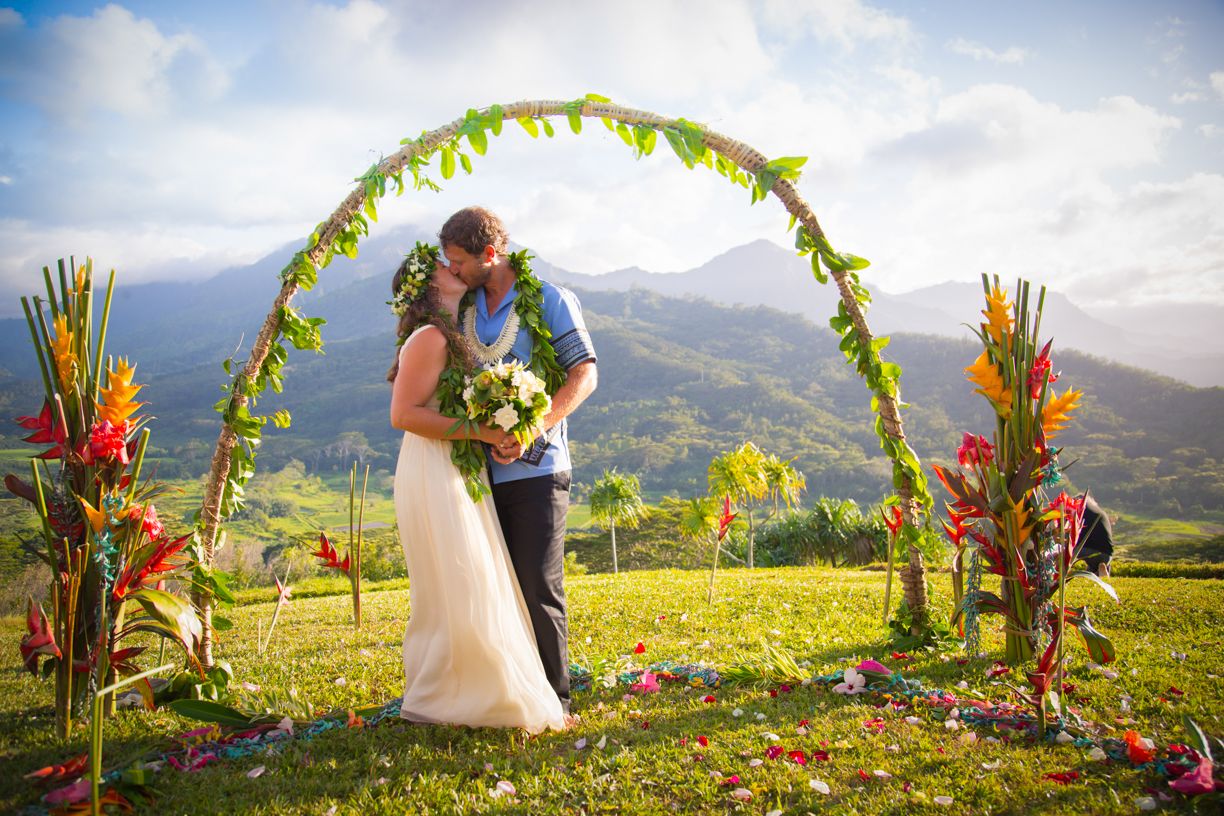Tropical wedding ceremony setup with mountain backdrop and colorful floral arrangements.
