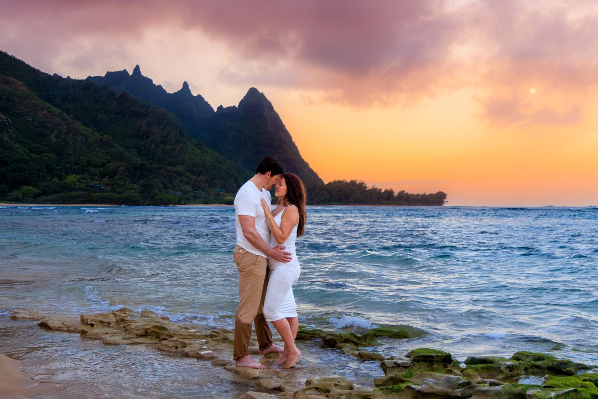 Romantic beach engagement session during a vibrant Hawaiian sunset.