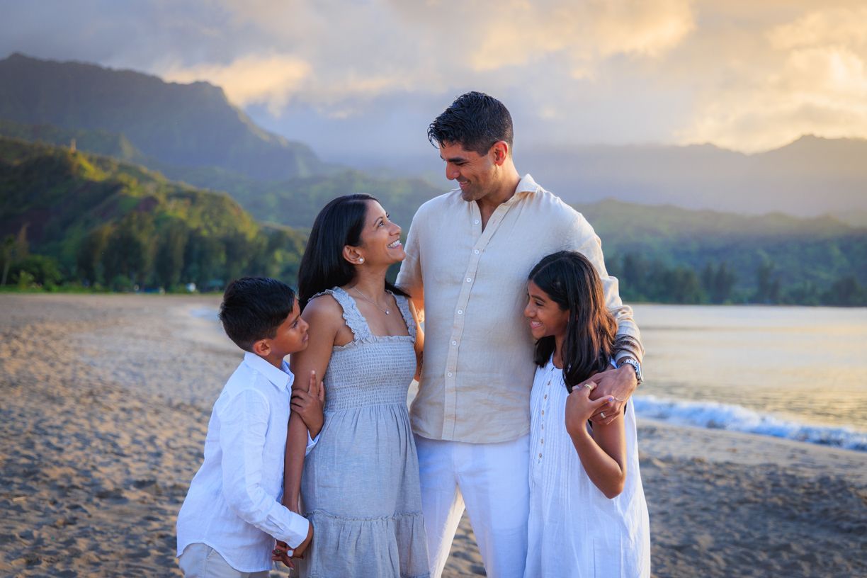Family beach portrait session with mountains and sunset backdrop in Hawaii.