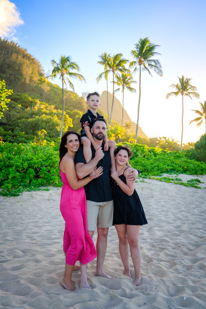 Fun group beach photos with palm trees and mountains during sunset in Hawaii.