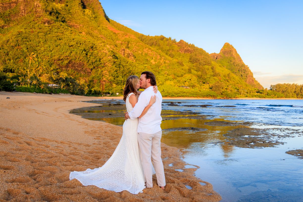 A romantic beach photoshoot with golden mountains and blue waters creating a stunning natural backdrop.