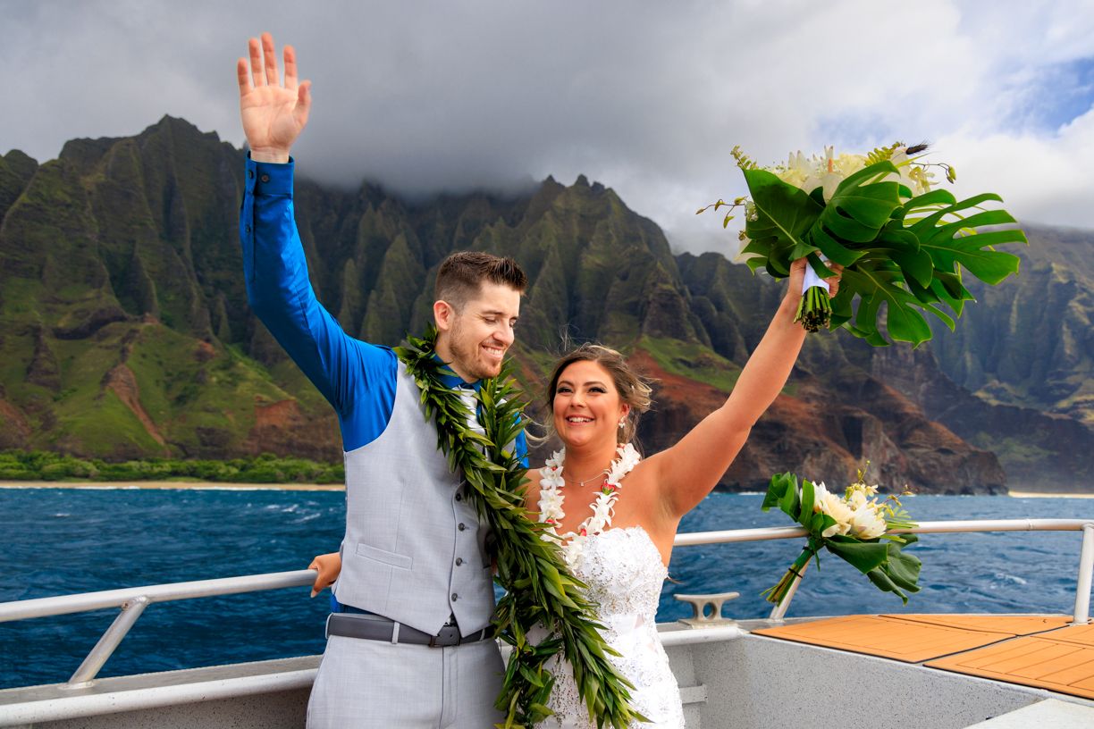 Wedding celebration aboard boat with Na Pali coast cliffs of Kauai in background.