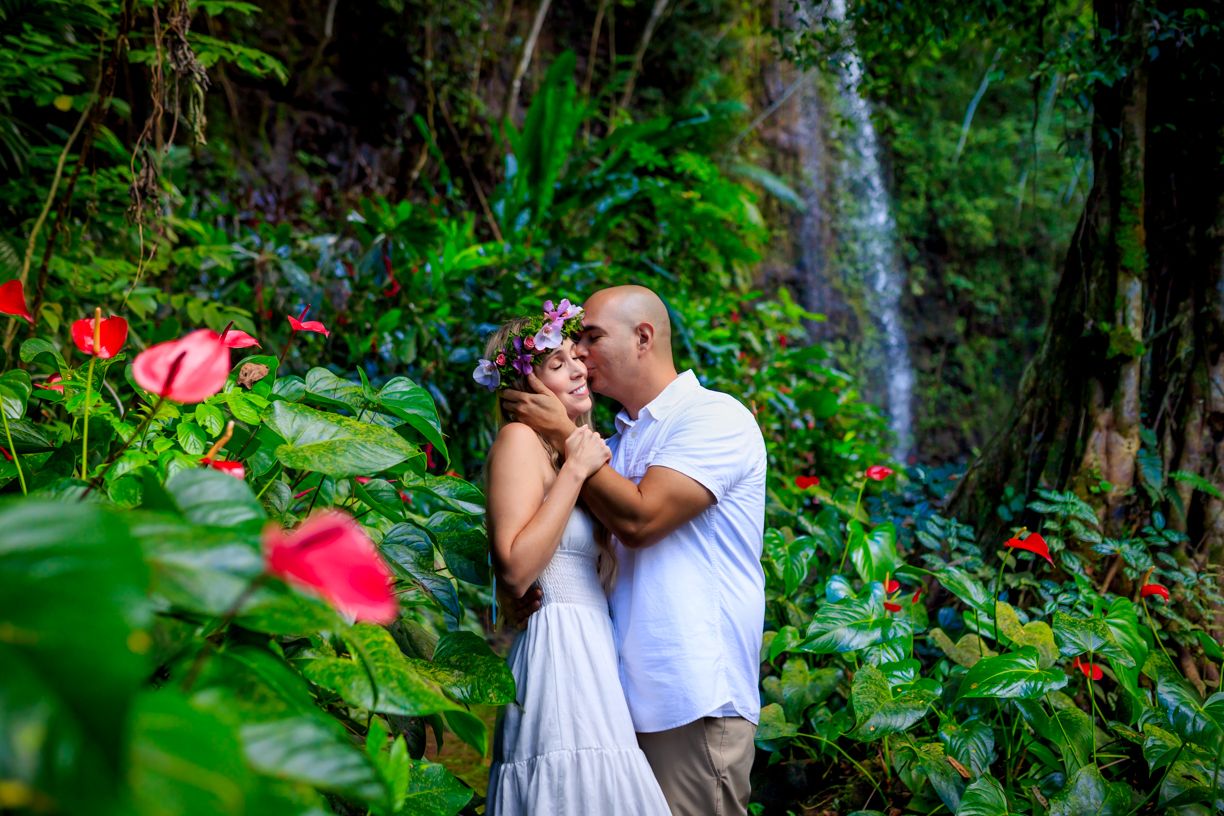 Romantic moment among tropical flowers and waterfall in lush garden setting.