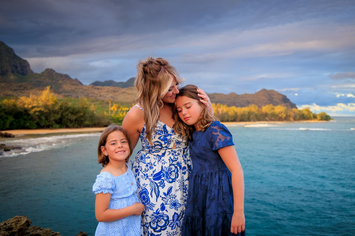 Group wearing coordinated blue and white outfits poses together against tropical ocean backdrop.