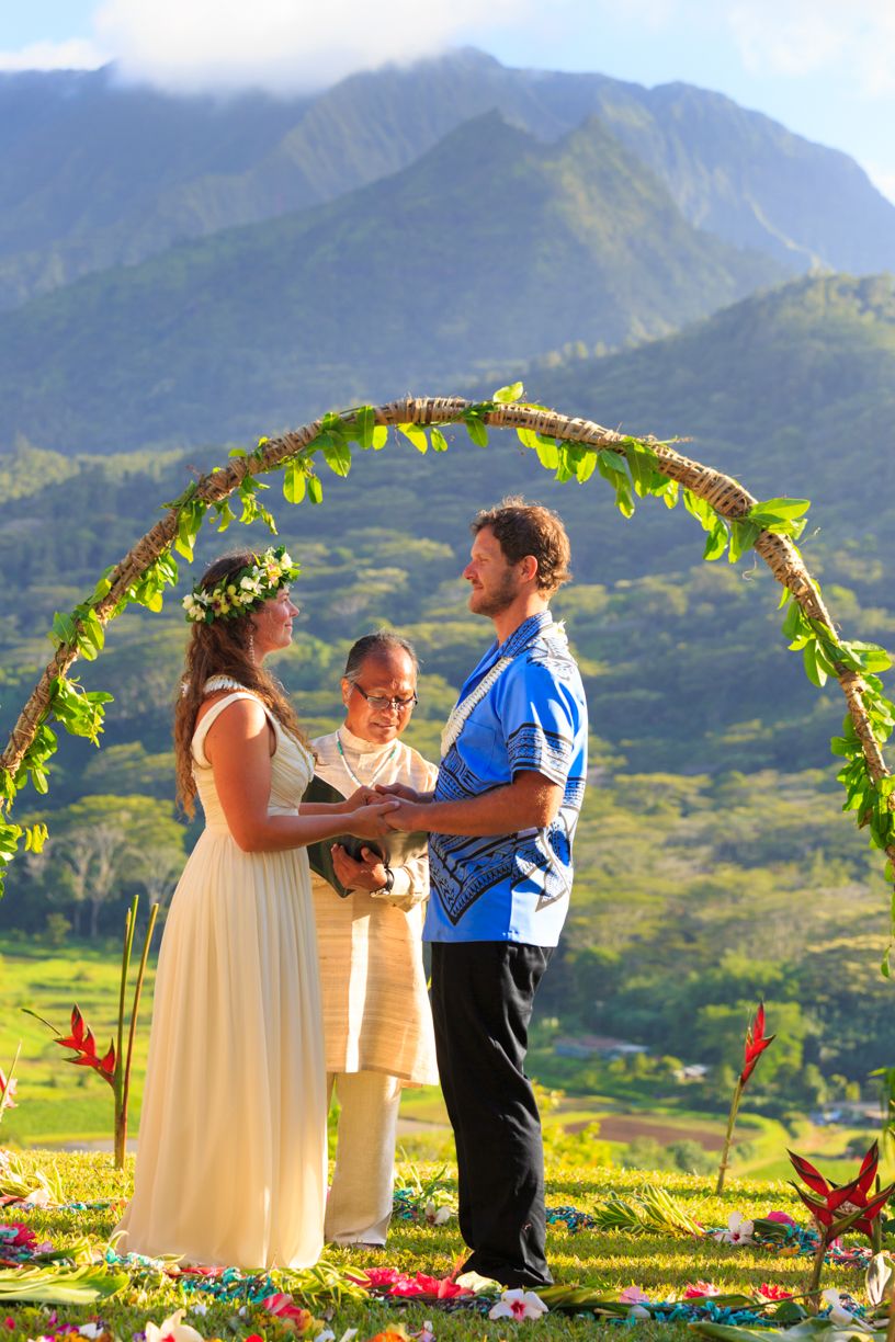 Wedding ceremony under floral arch with majestic mountain landscape in background.