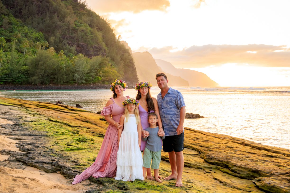 Family beach photoshoot during golden hour with mountains and ocean in background.