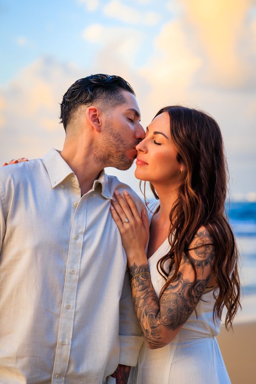 A romantic beach photoshoot captures intimate moments between two people at sunset.