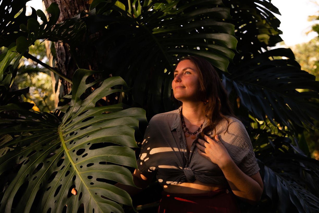 Atmospheric portrait among tropical monstera leaves in natural lighting.
