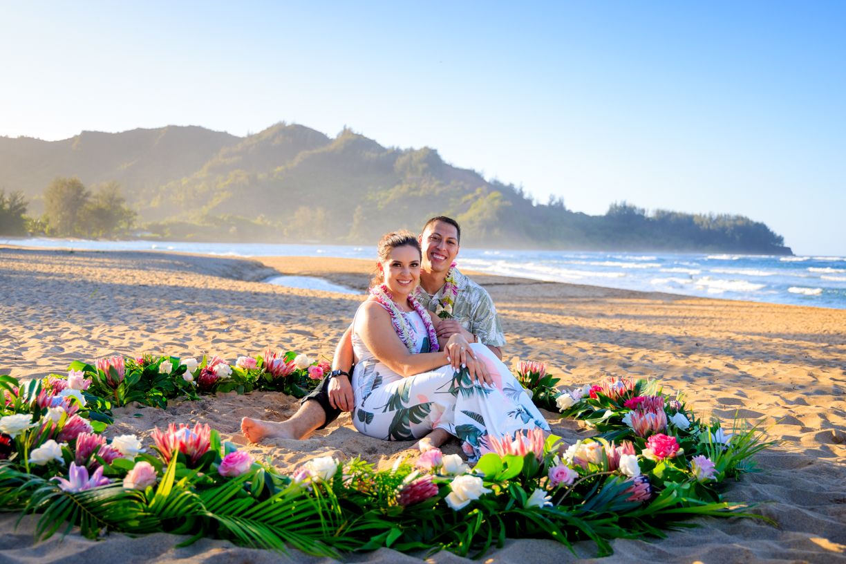 A scenic beach proposal setup with flower circle and mountains in the background.