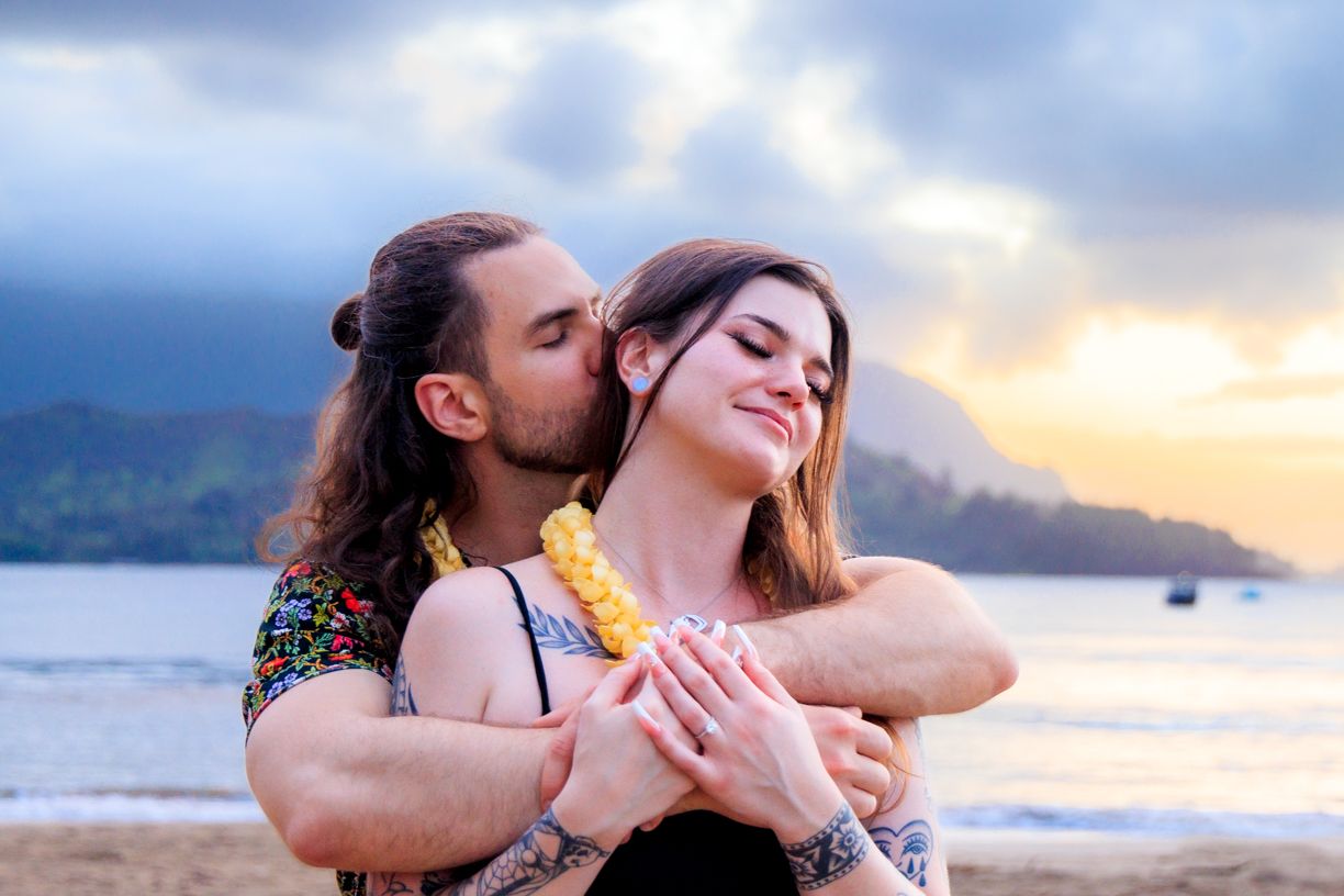 Romantic beach moment at sunset with mountains and ocean in the background.