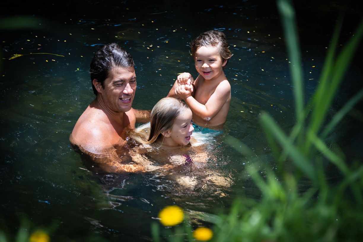Kaua'i family enjoys intimate moments in a secluded tropical swimming hole surrounded by lush vegetation.