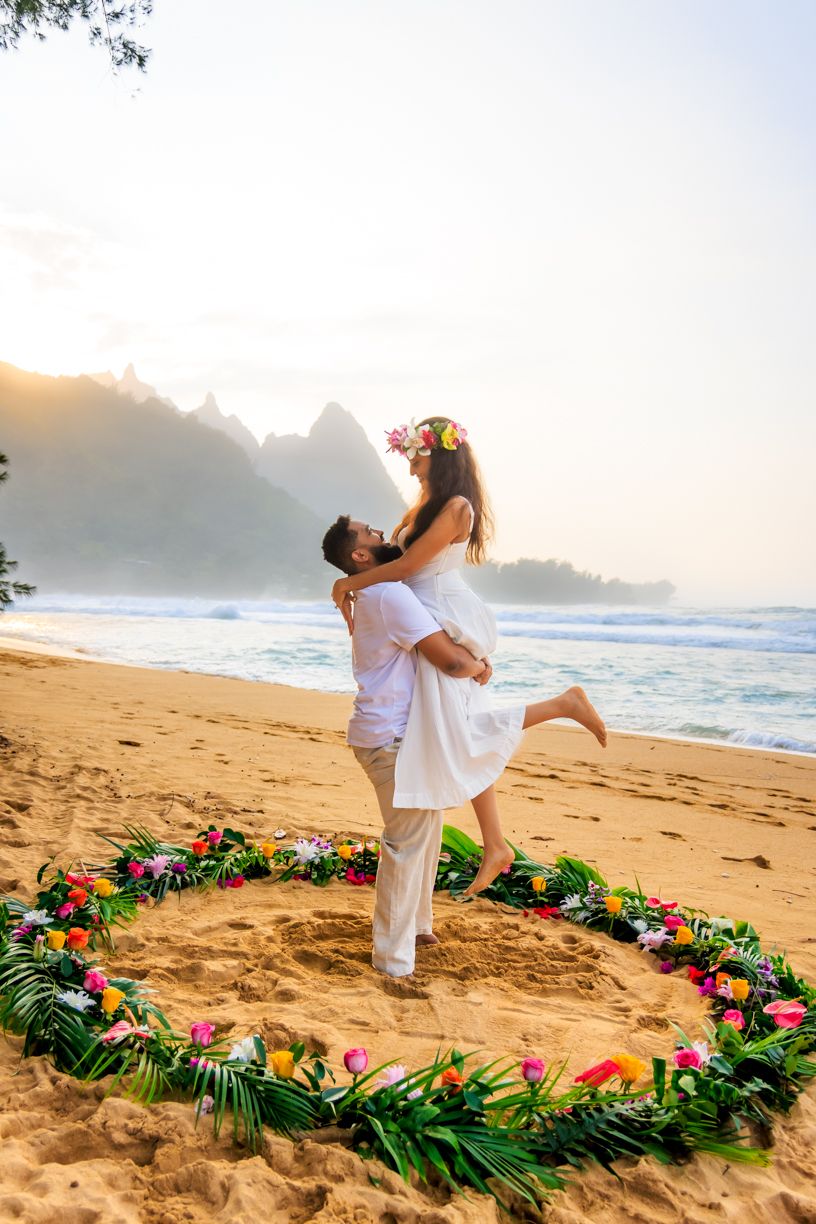 Romantic surprise proposal with floral arrangement made of tropical flowers and palm leaves at Tunnels Beach