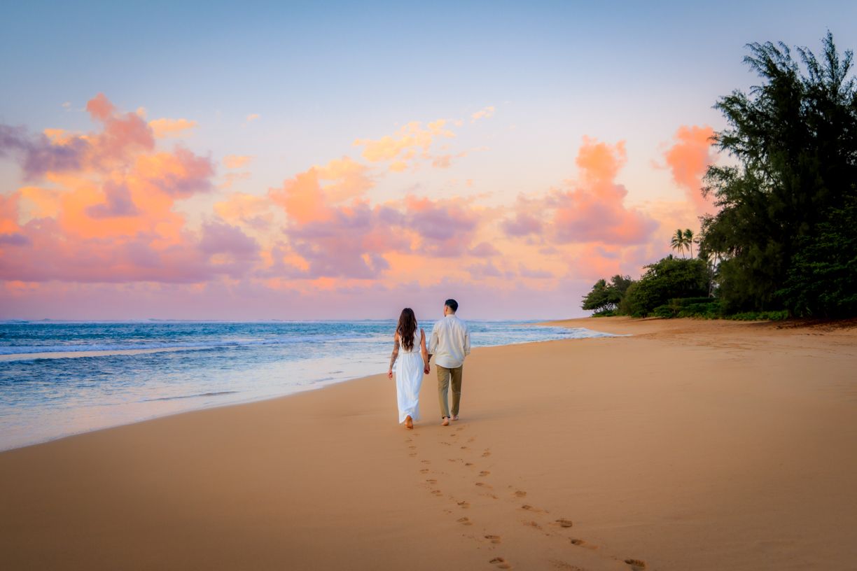 Romantic sunset beach walk leaving footprints in the sand along Hawaiian shoreline.