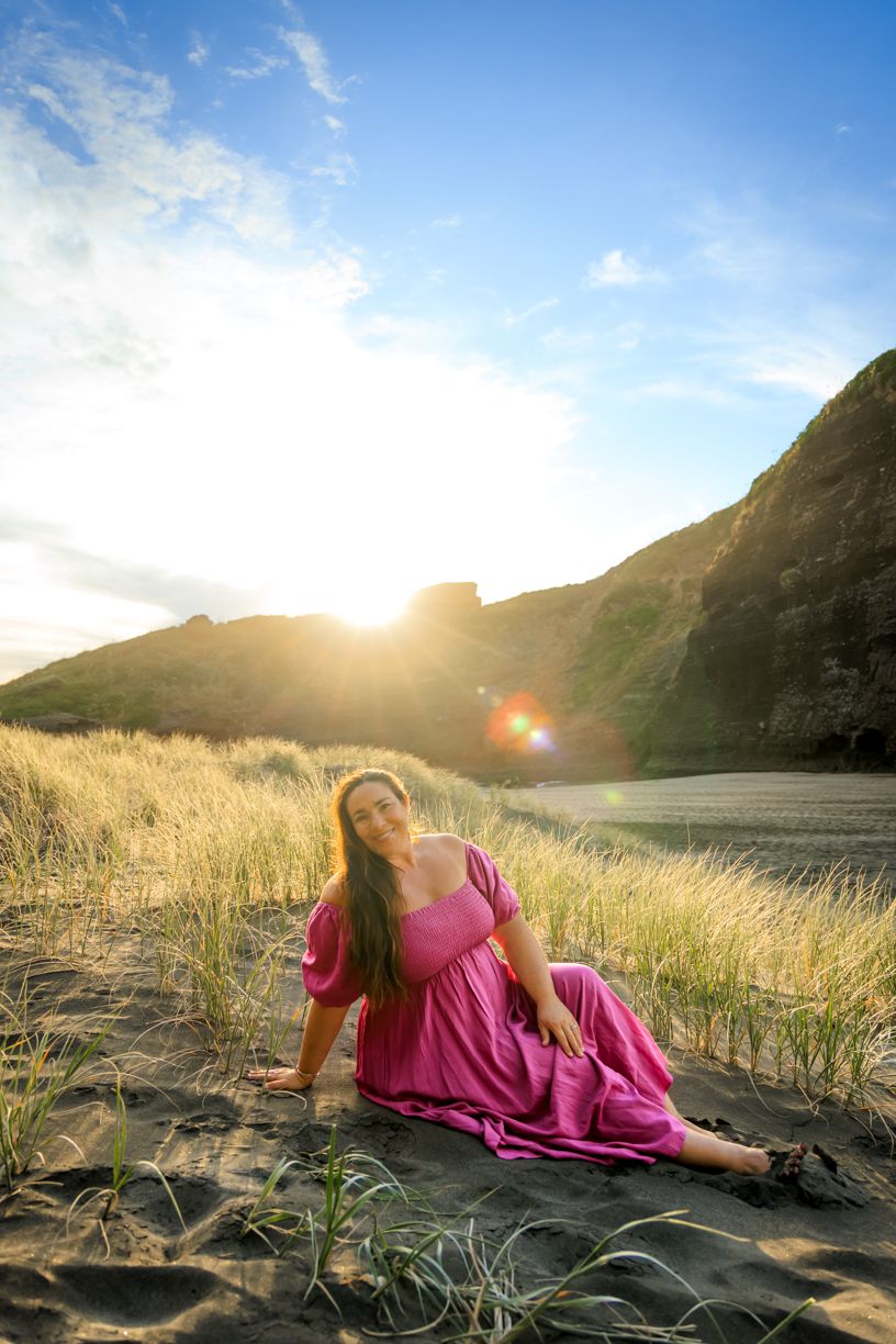 Golden sunlight illuminates coastal grass field against mountain backdrop.