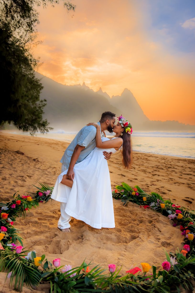 Romantic beach scene with tropical flowers and golden sunset.