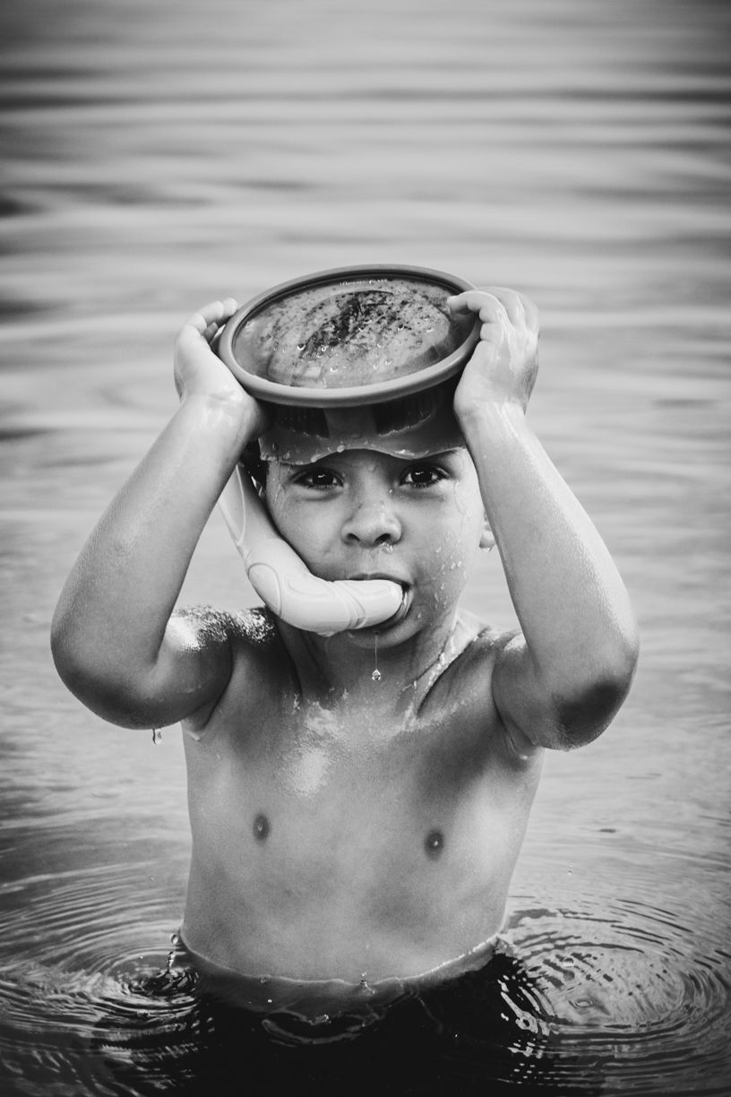 Black and white photo of child playing in water with reflective surface.