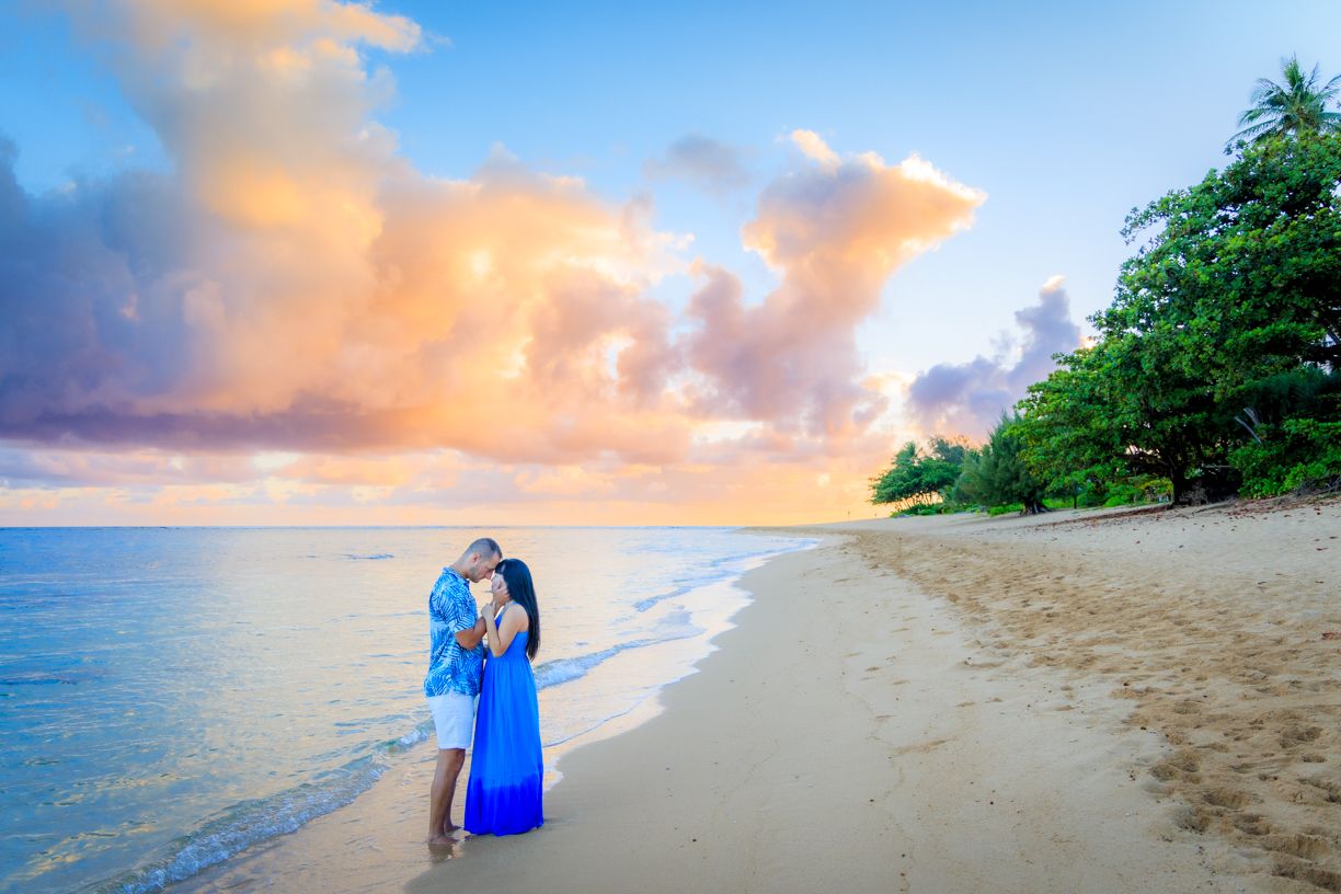 Beautiful sunset beach landscape with palm trees and soft waves rolling onto shore.