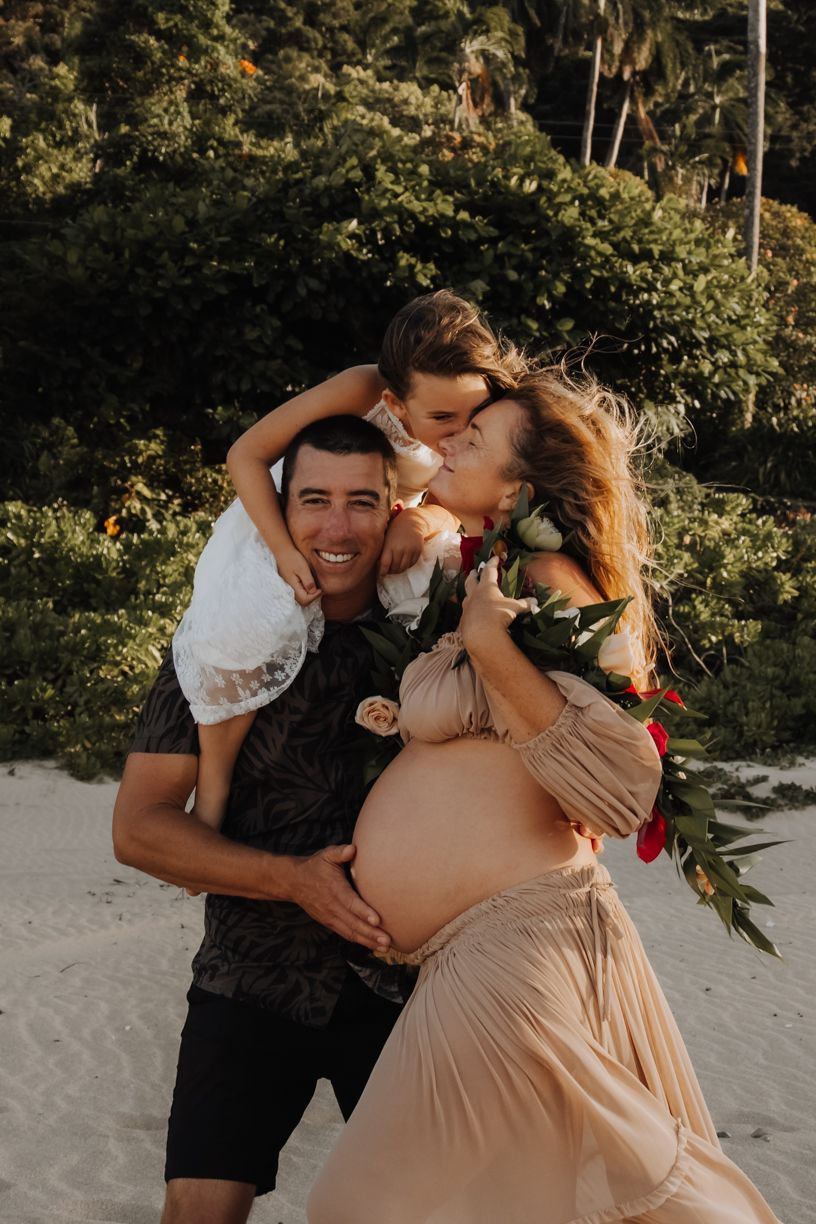 Joyful maternity moments captured on a tropical beach at golden hour.