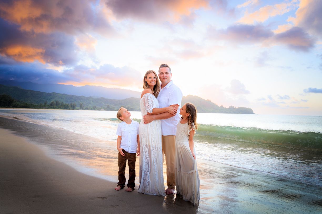 Family walking along shoreline during golden hour at beach.