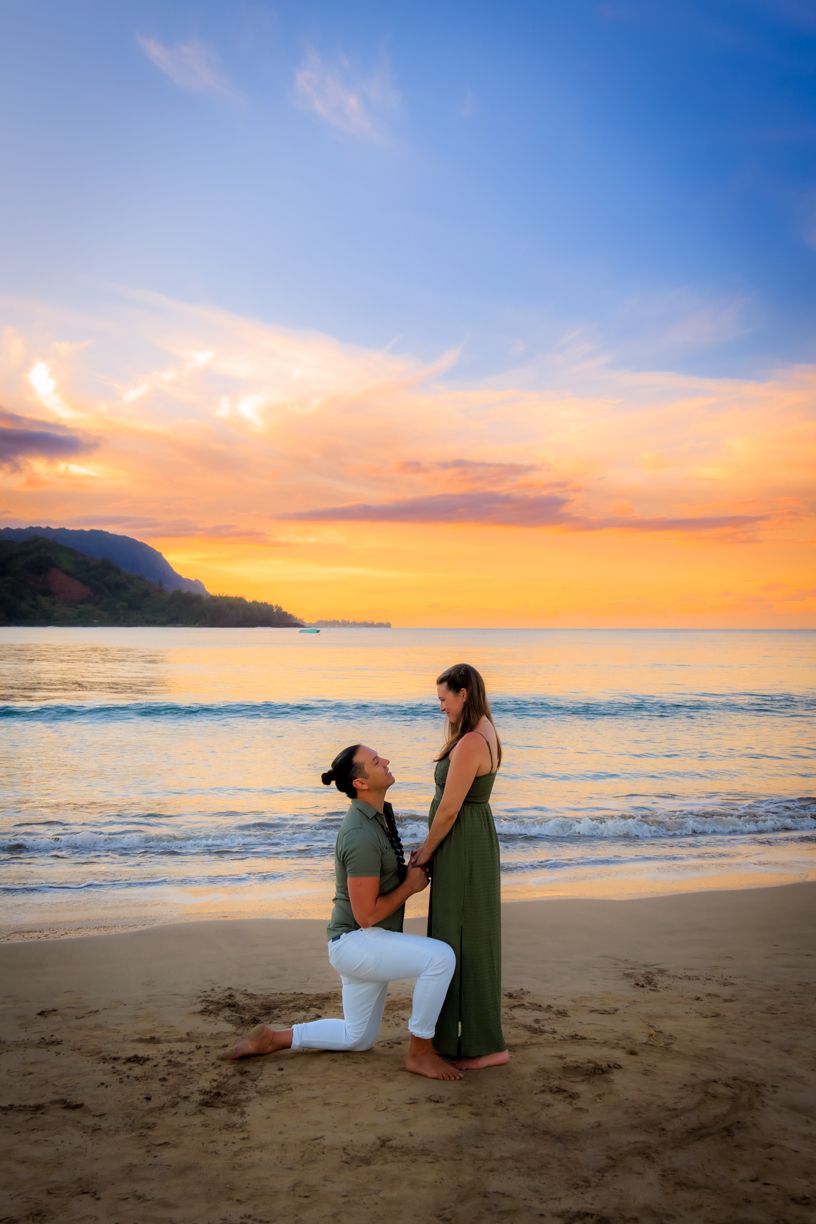 Marriage proposal on sandy beach with dramatic sunset sky.