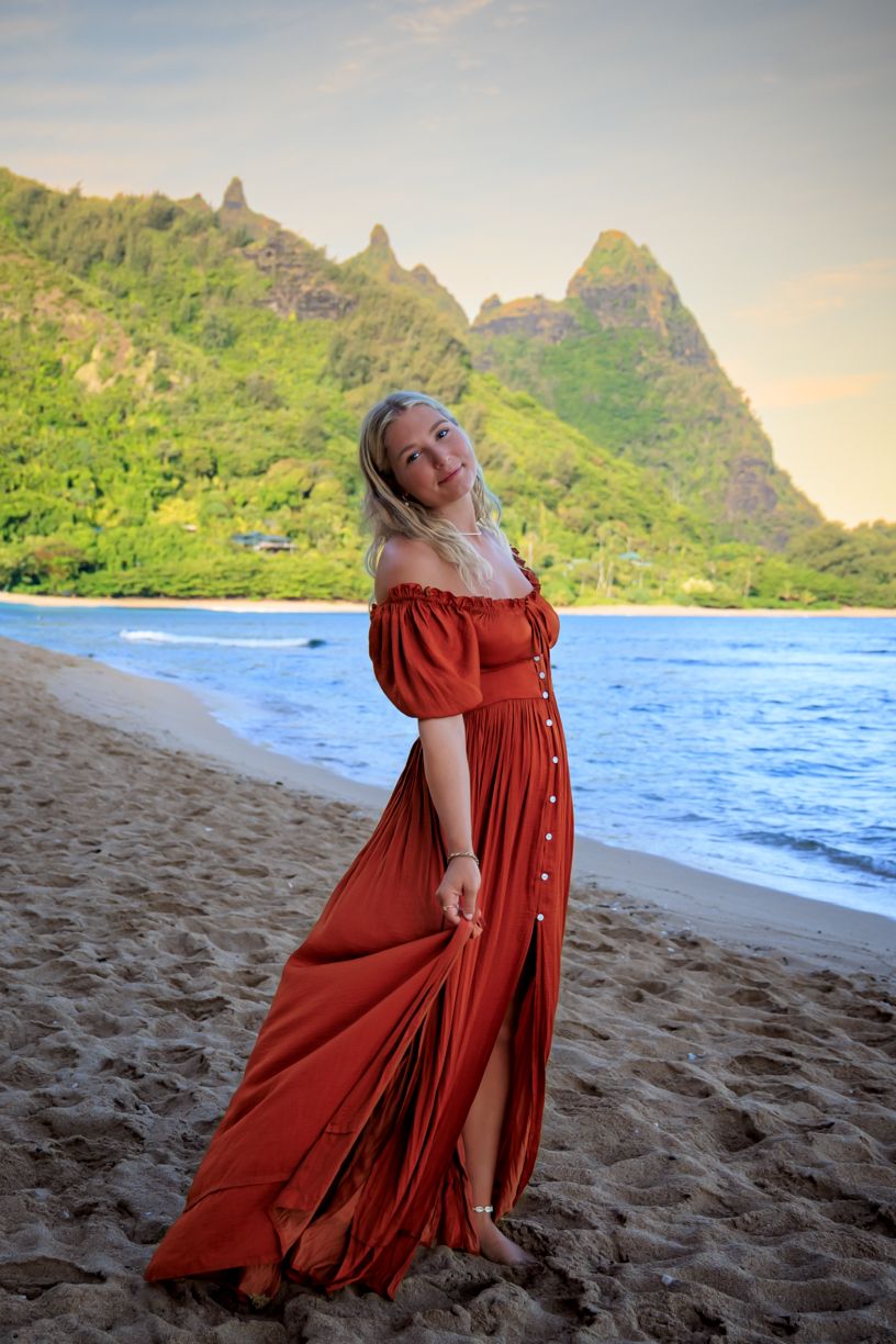 Flowing red dress movement captured against backdrop of Hawaiian mountains and ocean.