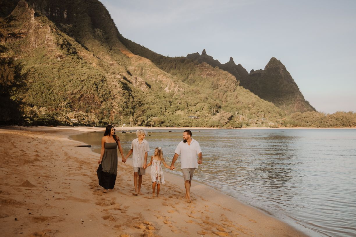 Family walking along scenic Hawaiian coastline with mountains and ocean views.
