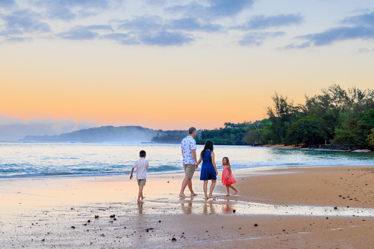 Scenic beach landscape with distant figures walking along shoreline at sunset.