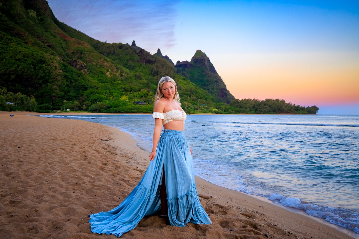 Light blue dress flowing in ocean breeze on tropical beach with mountains in background.