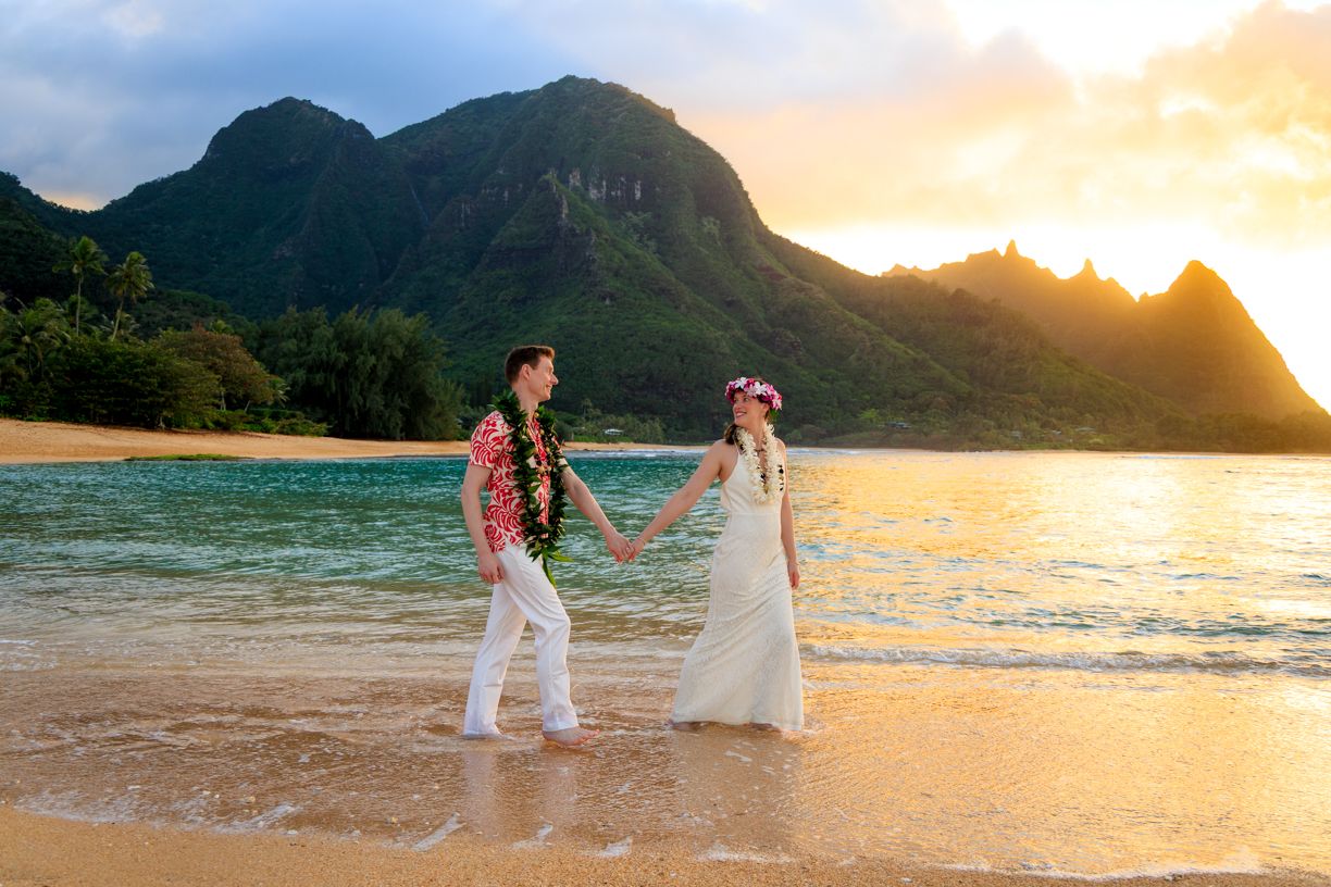 Romantic beach wedding photoshoot at sunset with mountains and ocean in background.