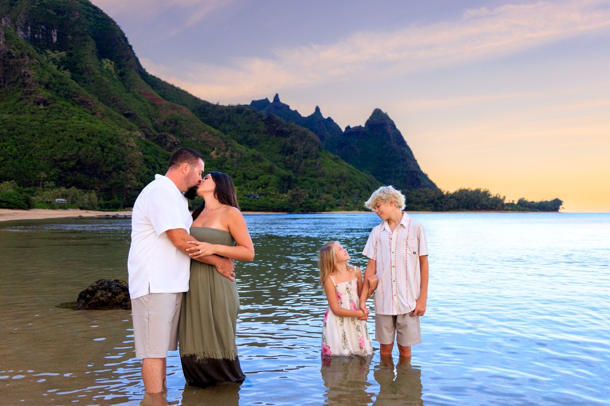 Sunset beach photography session with dramatic mountain backdrop in Hawaii.