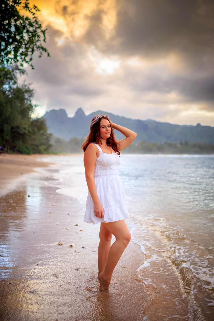 Sunset photoshoot at a tropical beach with dramatic clouds and mountains in the background.