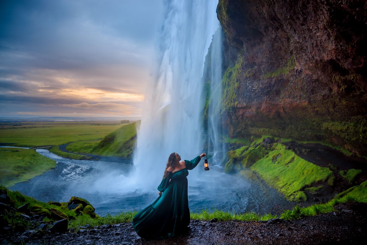 Dramatic waterfall cascading down moss-covered cliffs with a rainbow in the mist.