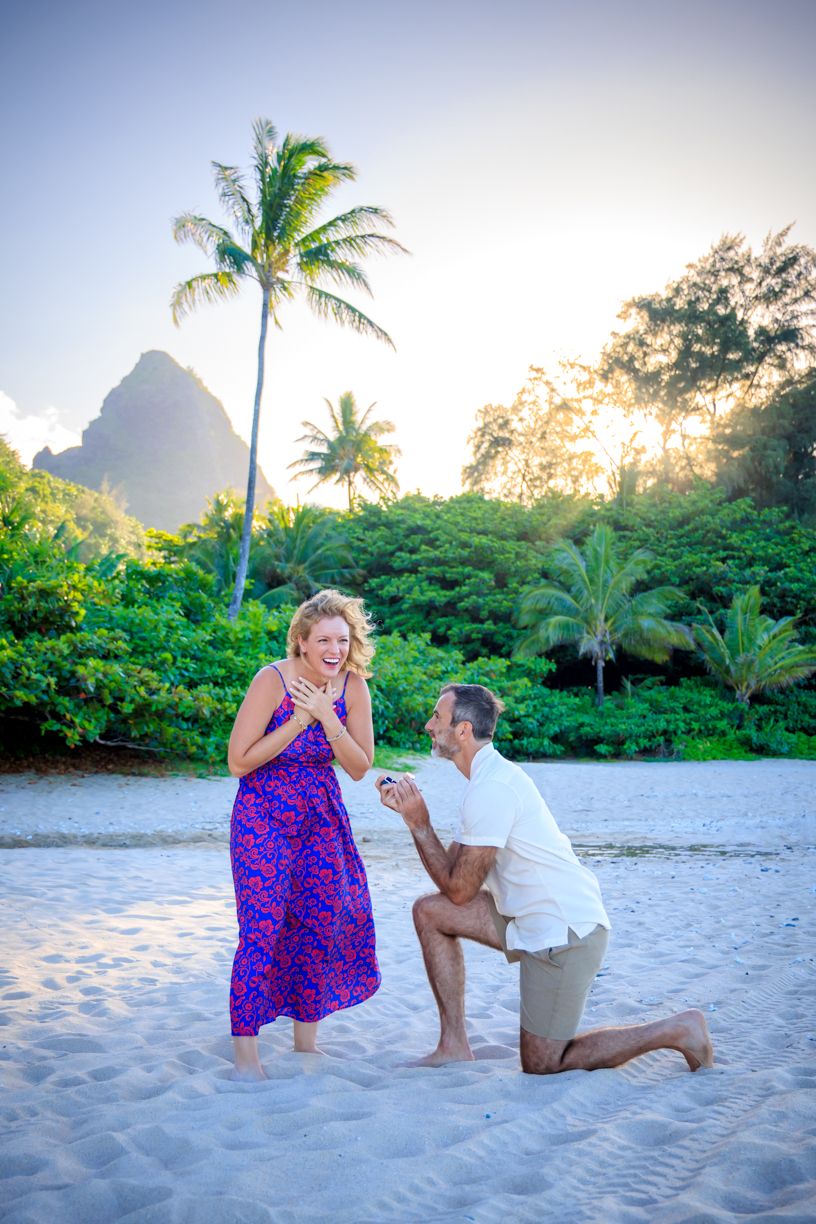 A romantic beach proposal sequence with palm trees and mountains in Hawaii at sunset.