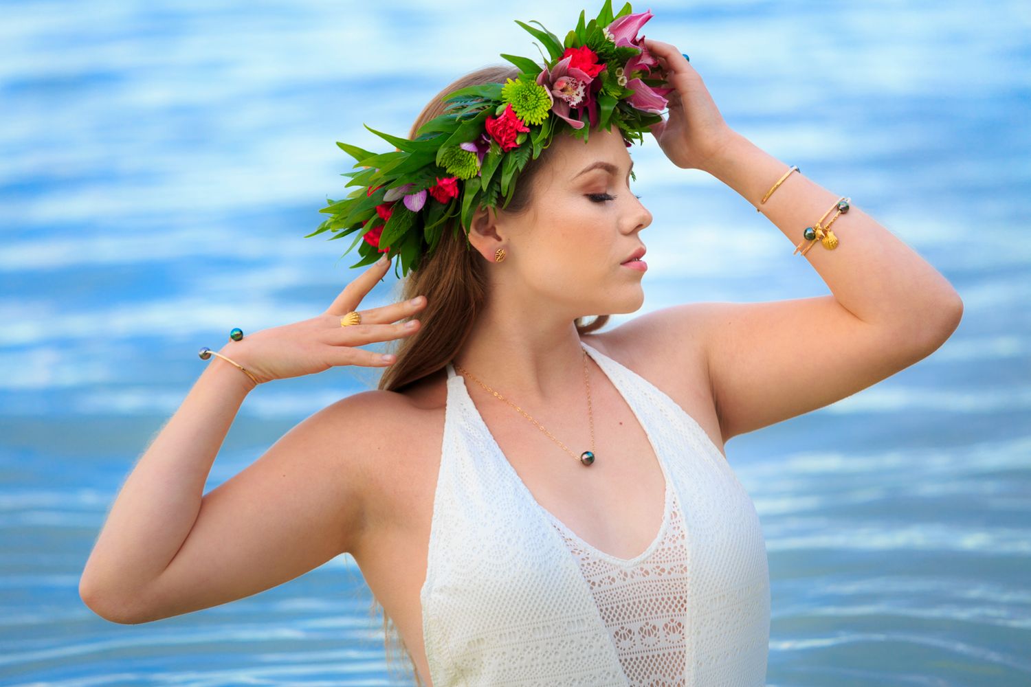 Beachside portrait with floral crown and white swimsuit against blue water.