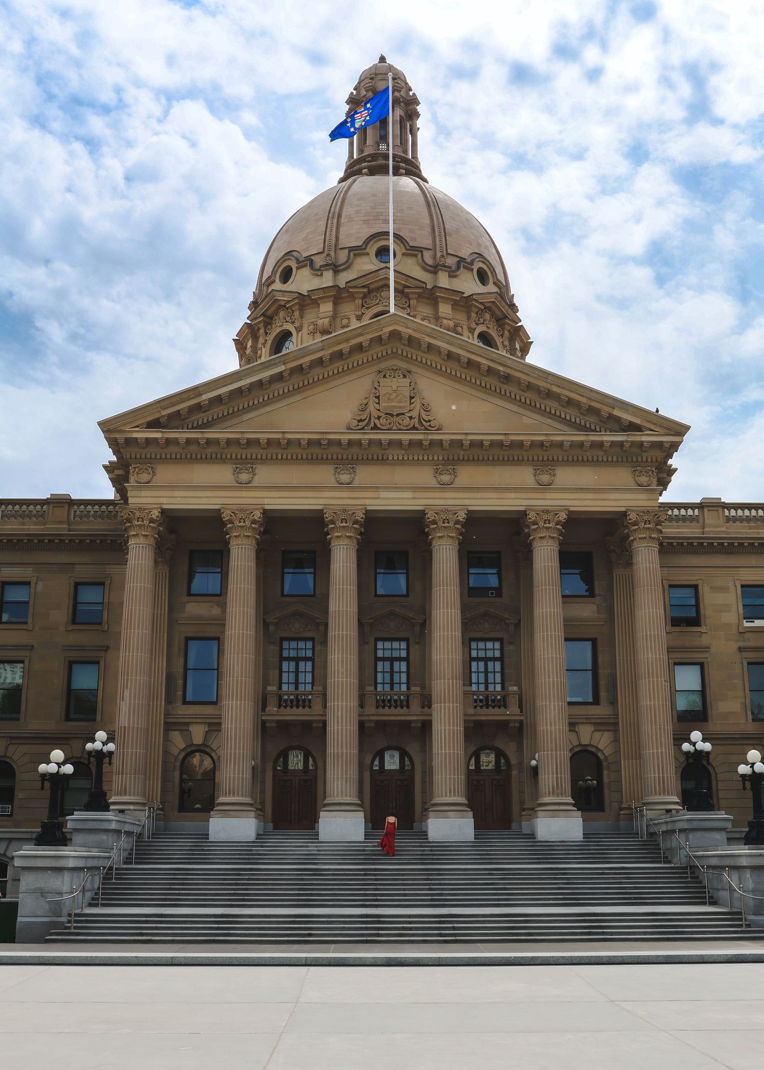 Grand neoclassical Alberta Legislature Building with dome and columns under cloudy blue sky.