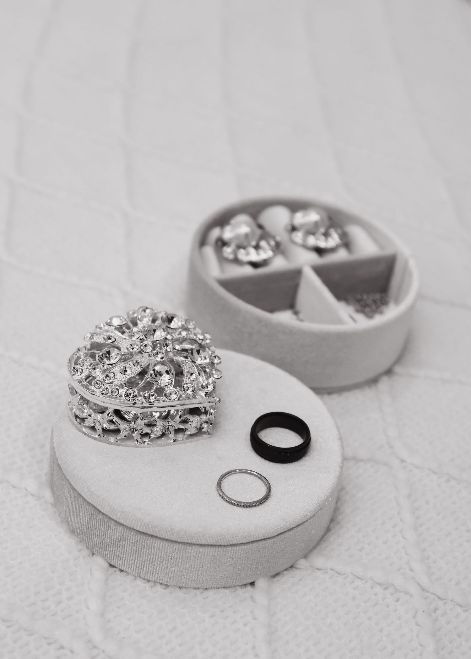 Wedding rings and crystal jewelry displayed in a gray velvet jewelry box.