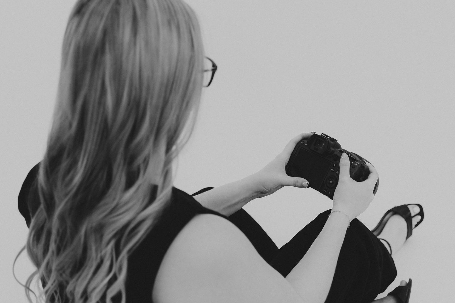 Side view of photographer with long hair holding camera against white background.
