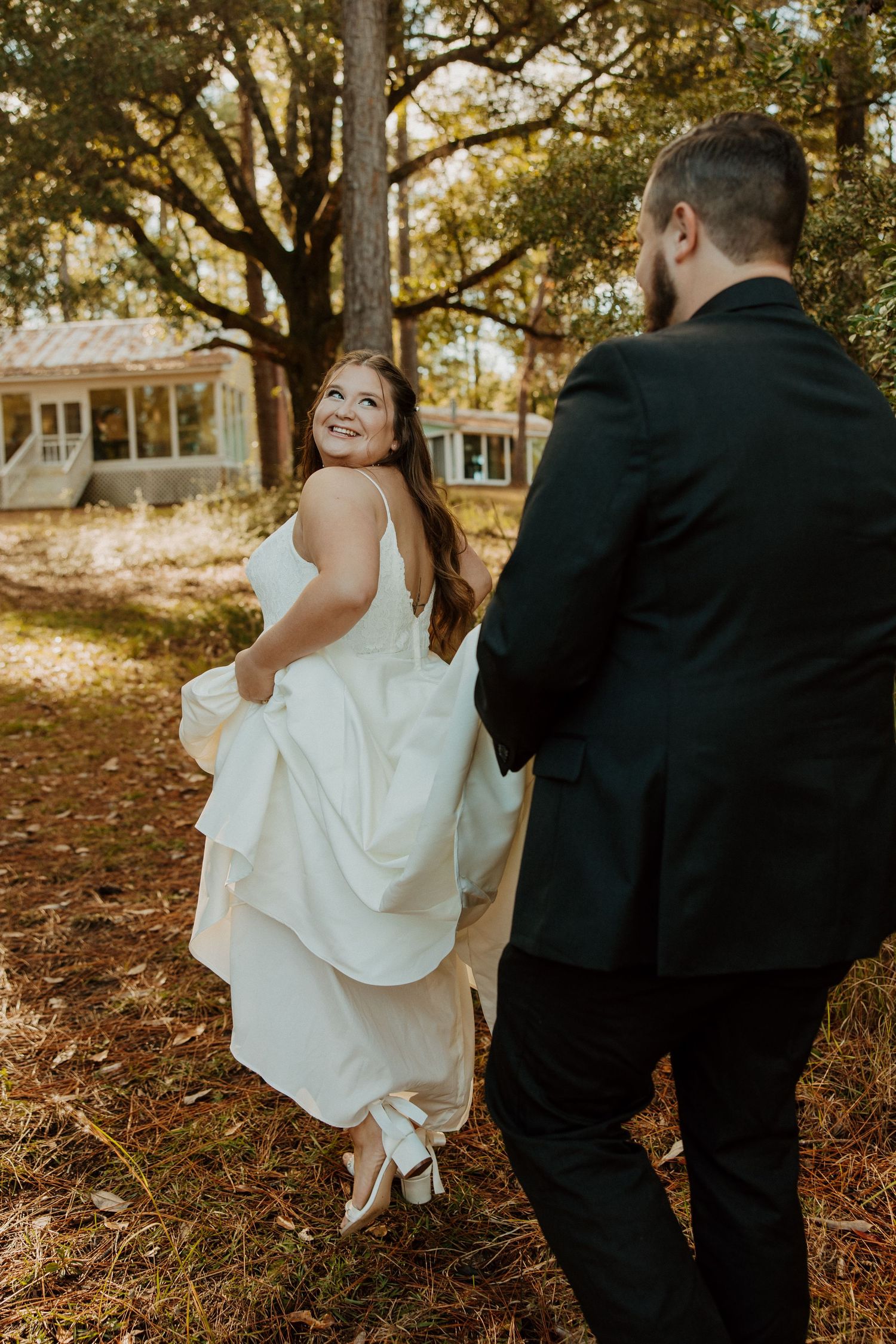 A playful wedding moment captured as the bride twirls her dress in golden autumn light.