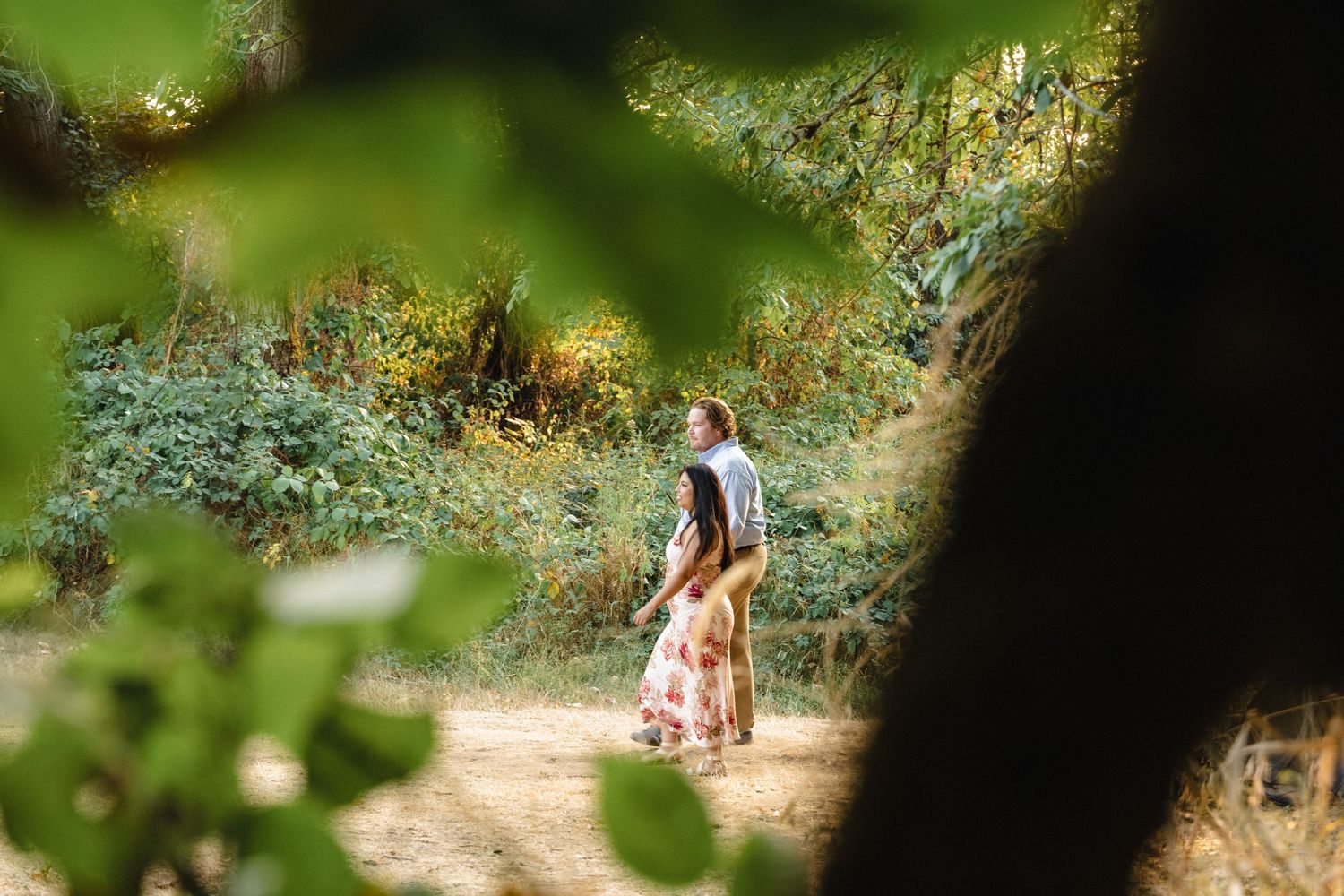 Natural foliage frames a romantic outdoor scene through leaves and branches.